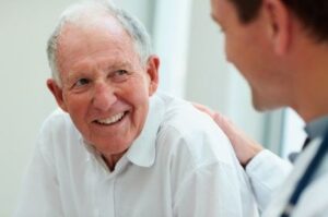 An older man talking with his doctor about the benefits of dentures.