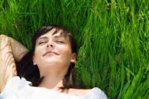 A young woman relaxing in the grass after enjoying sedation dentistry in Logan.