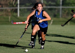 A young girl playing field hockey outside, a common cause of dental injury.
